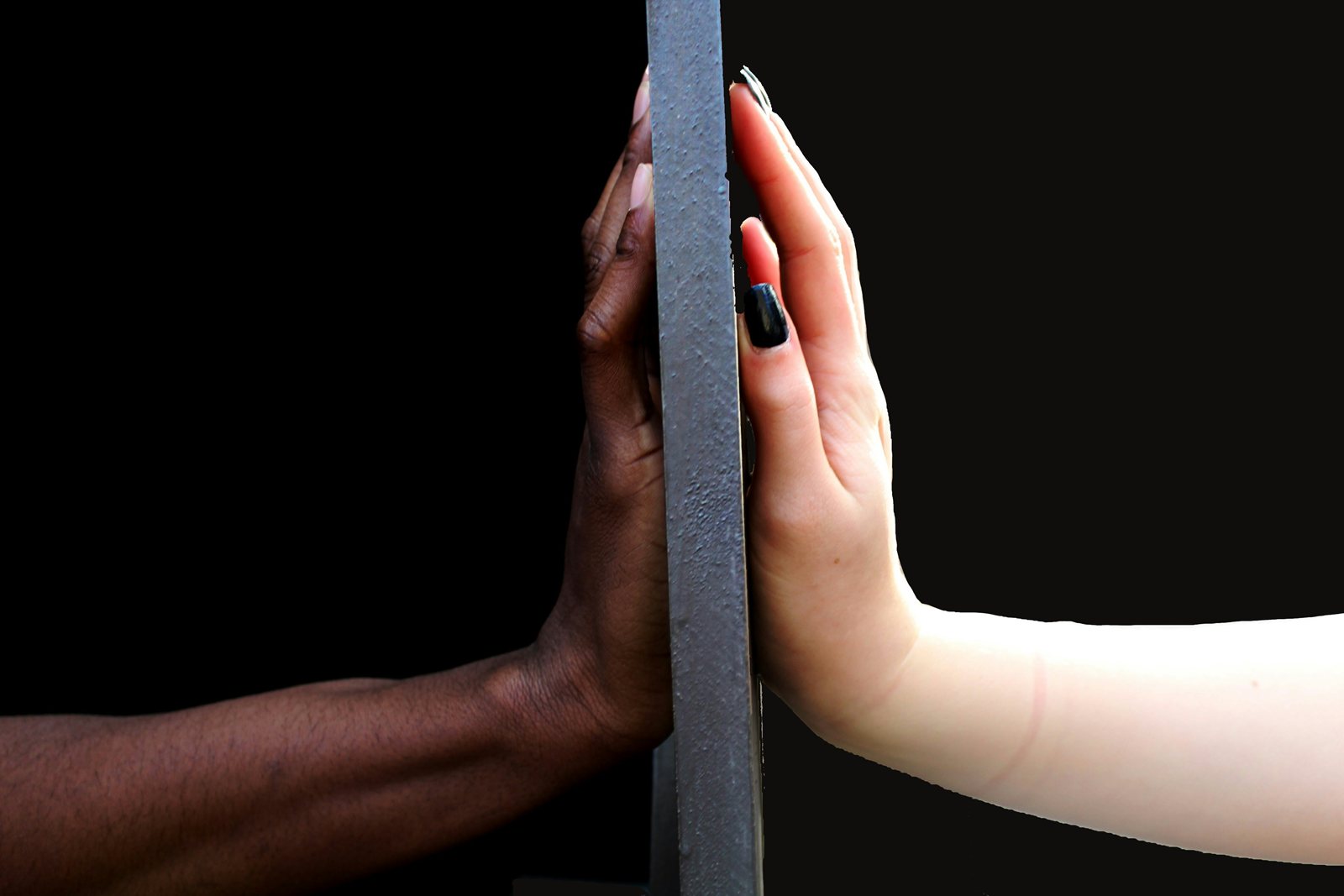 Two hands, one dark-skinned and one light-skinned, pressed to opposite sides of a slab.