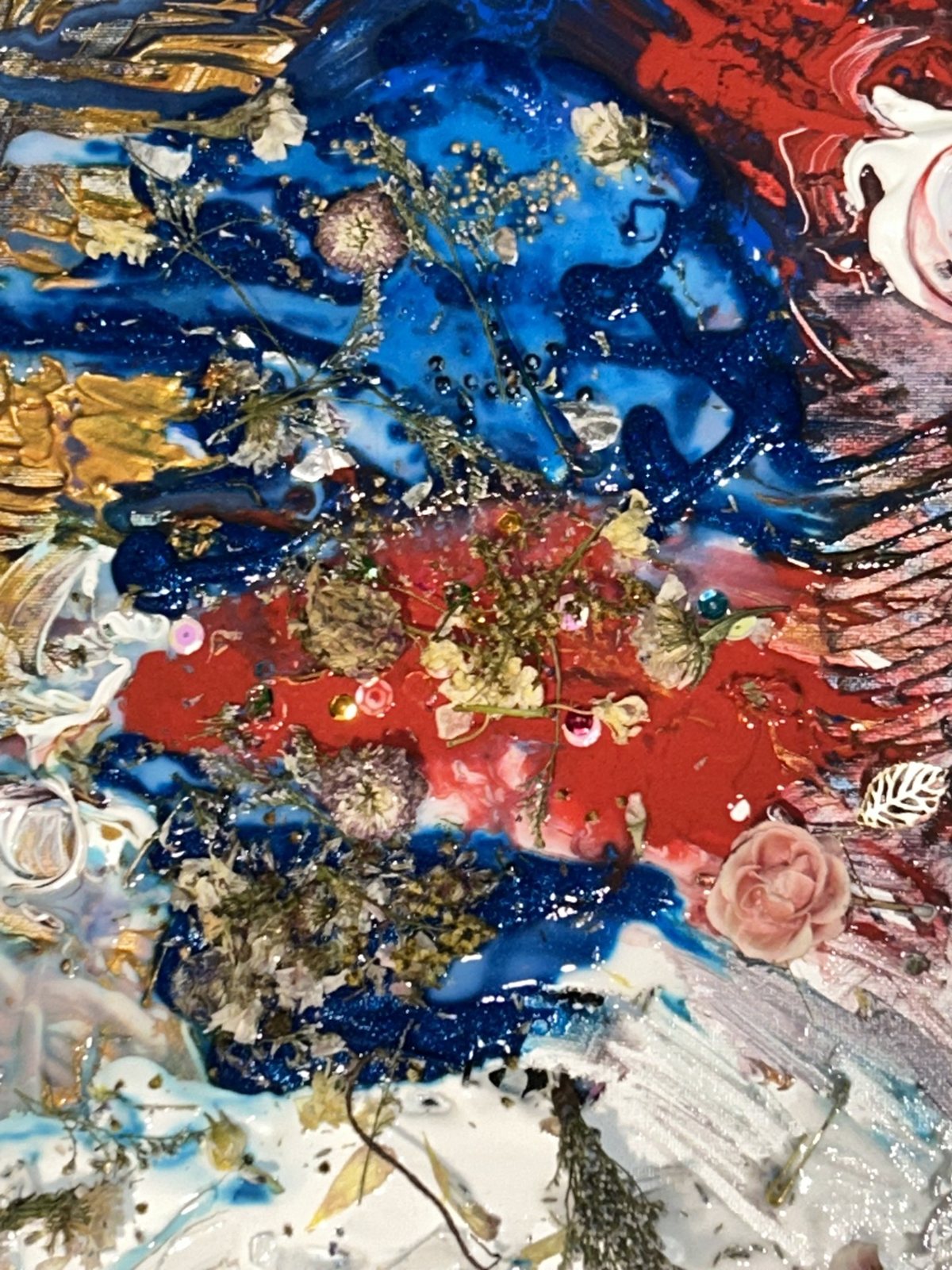 An abstract painting in red, blue and gold, thickly textured and gilded.