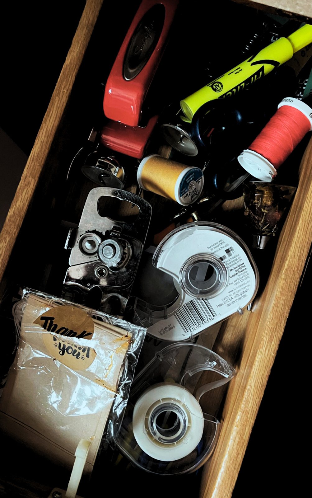 A drawer of odds and ends — rolls of tape, marker pens, a lighter, a paper bag.