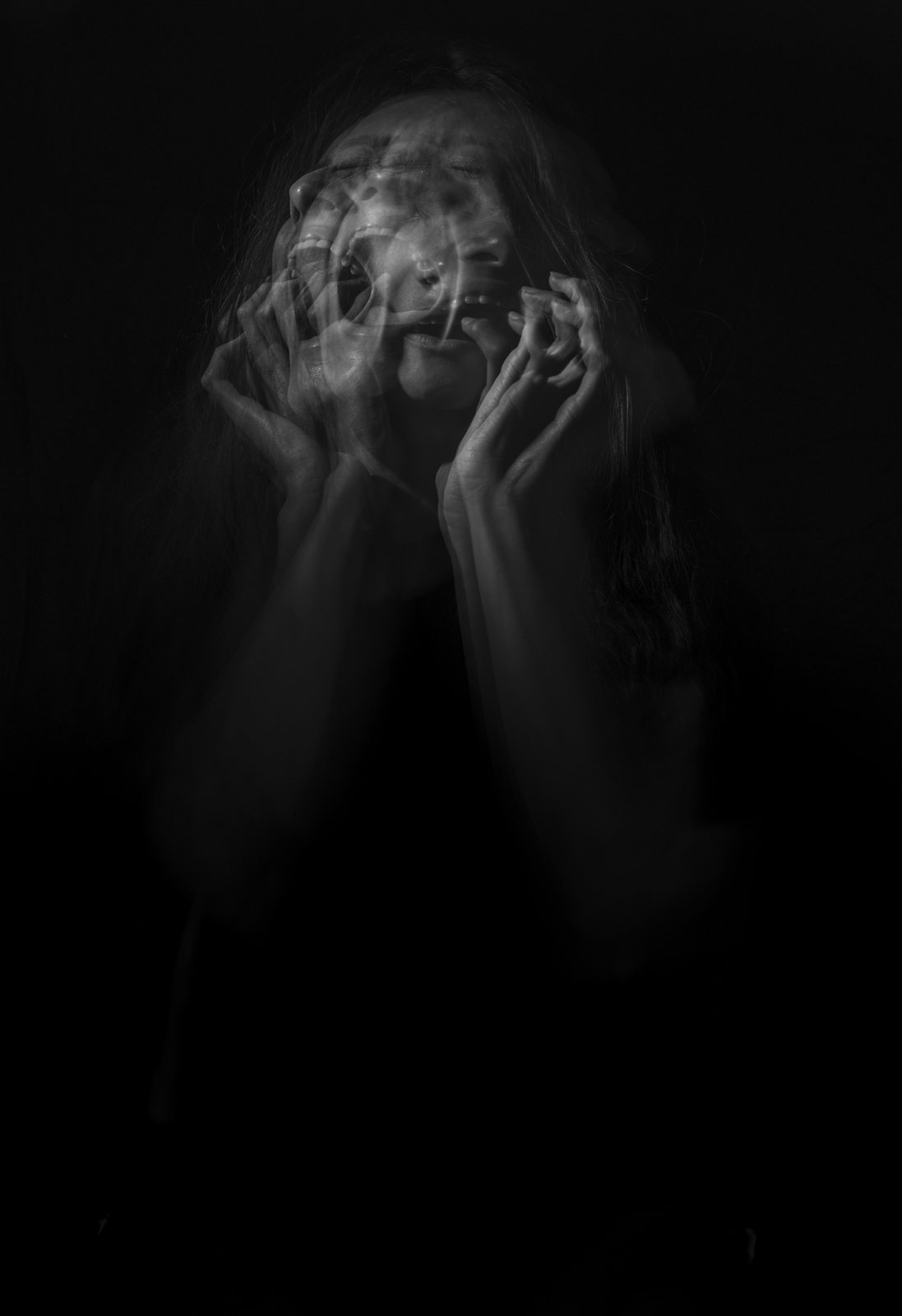 A long-exposure black-and-white figure with hands to the head, blurred into ghosting.
