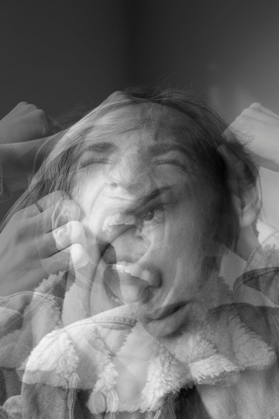 A blurred black-and-white portrait of a woman, head thrown back, mouth open.