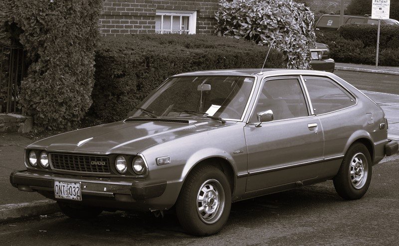 A silver 1980s hatchback parked at the kerb of a quiet suburban street.