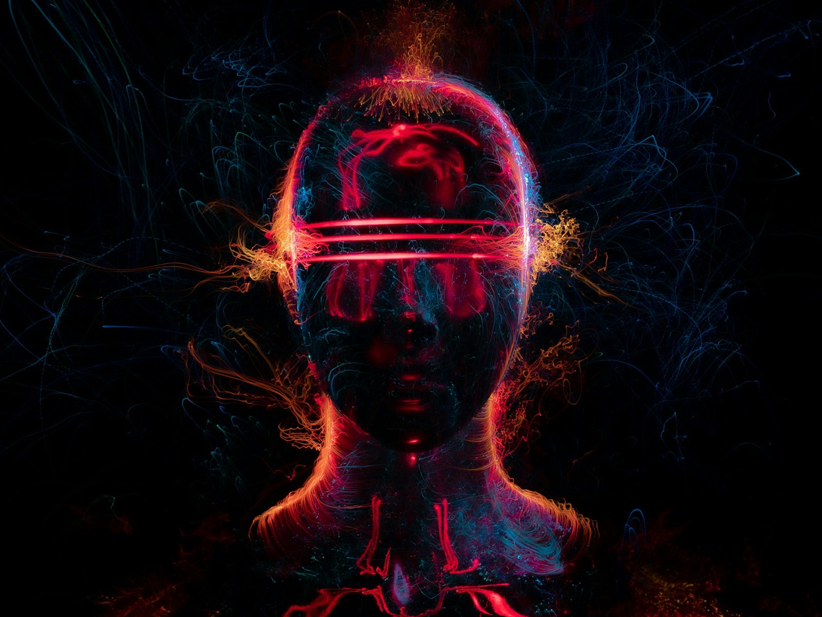 A head drawn in threads of red and blue light on black, the eyes banded.