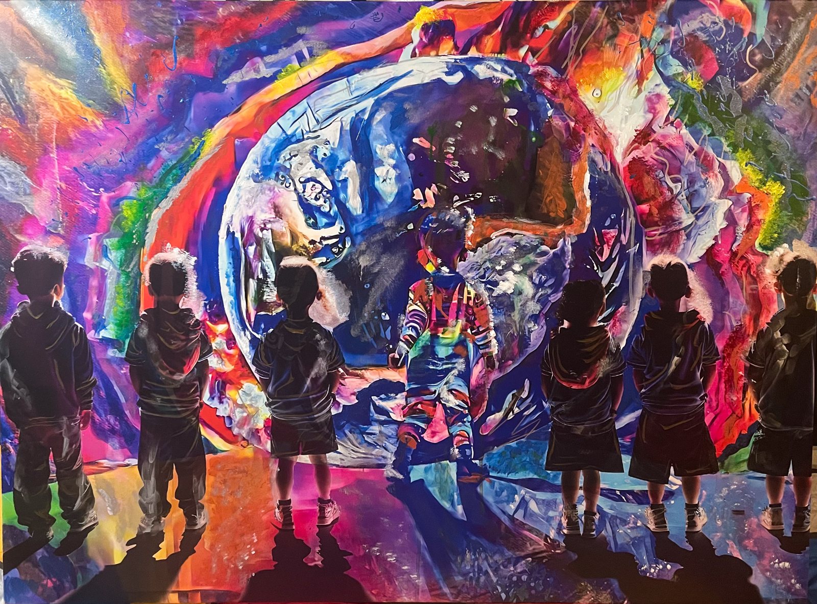 Children silhouetted in front of a vast swirling mural in every colour.