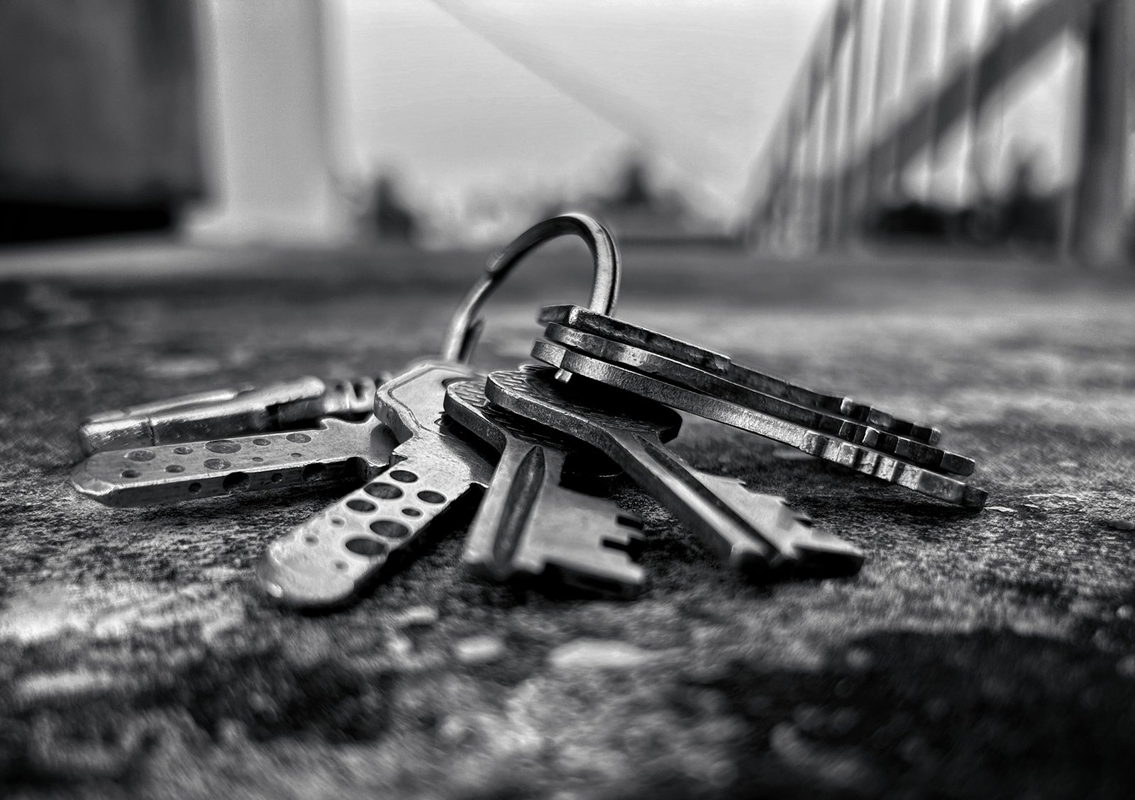 A bunch of keys lying on rough ground, in black and white.