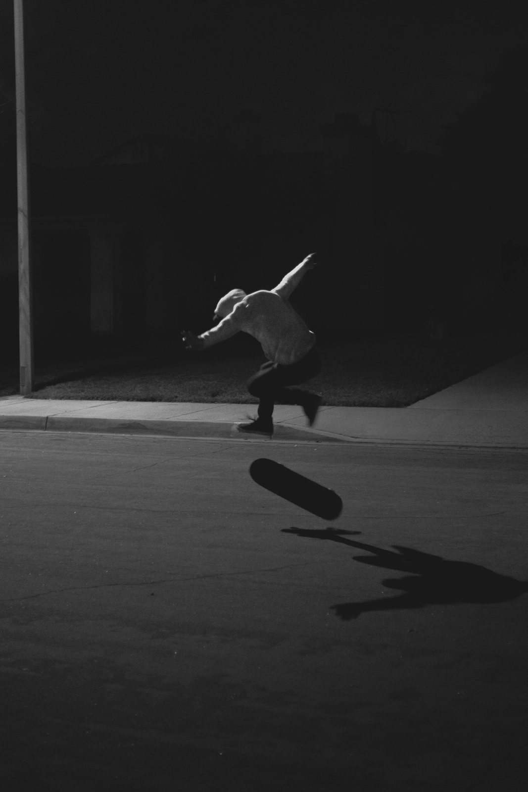 A skateboarder mid-air in an empty concrete space, in black and white.