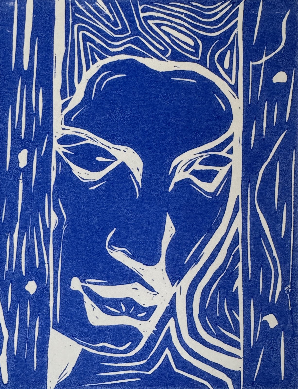 A blue and white linocut of a face, framed between two carved panels.